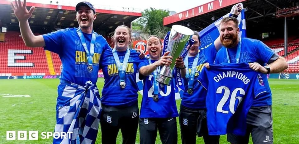 Celebrating team holding trophy and banners on pitch