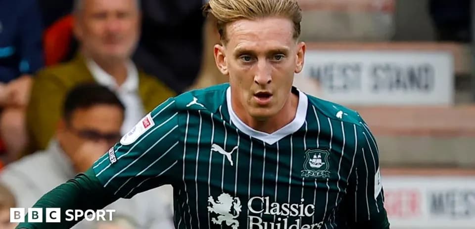 Player in green and black kit running on pitch