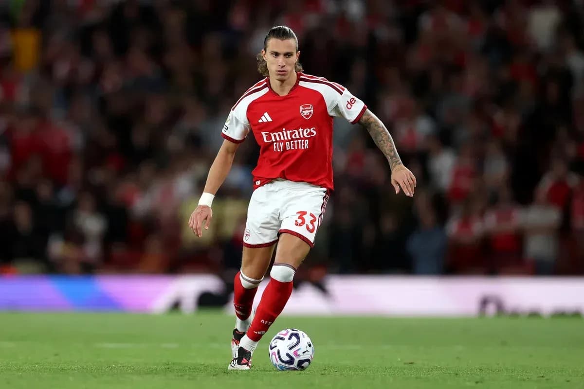 Player in Arsenal kit dribbling a soccer ball
