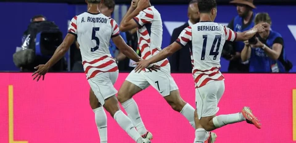 Three US players celebrating a goal on field