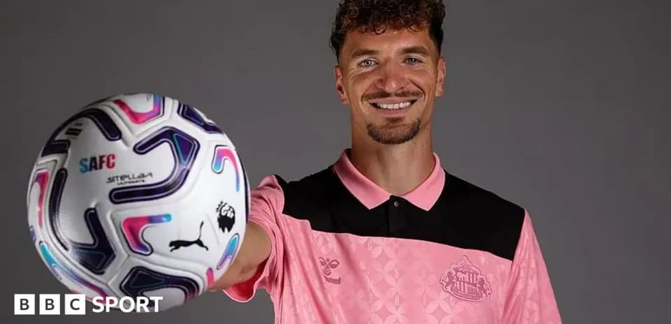 Player holding a football while smiling