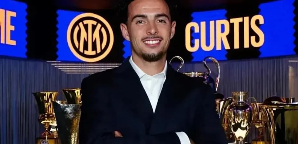 Man in suit posing with trophies in background