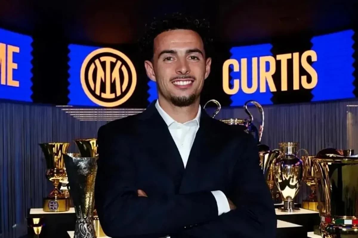 Man in suit posing with trophies in background