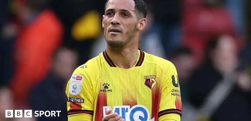 Player in Watford kit applauding fans after match