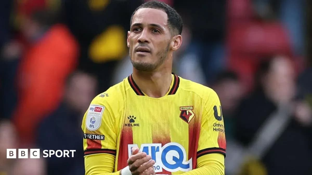Player in Watford kit applauding fans after match