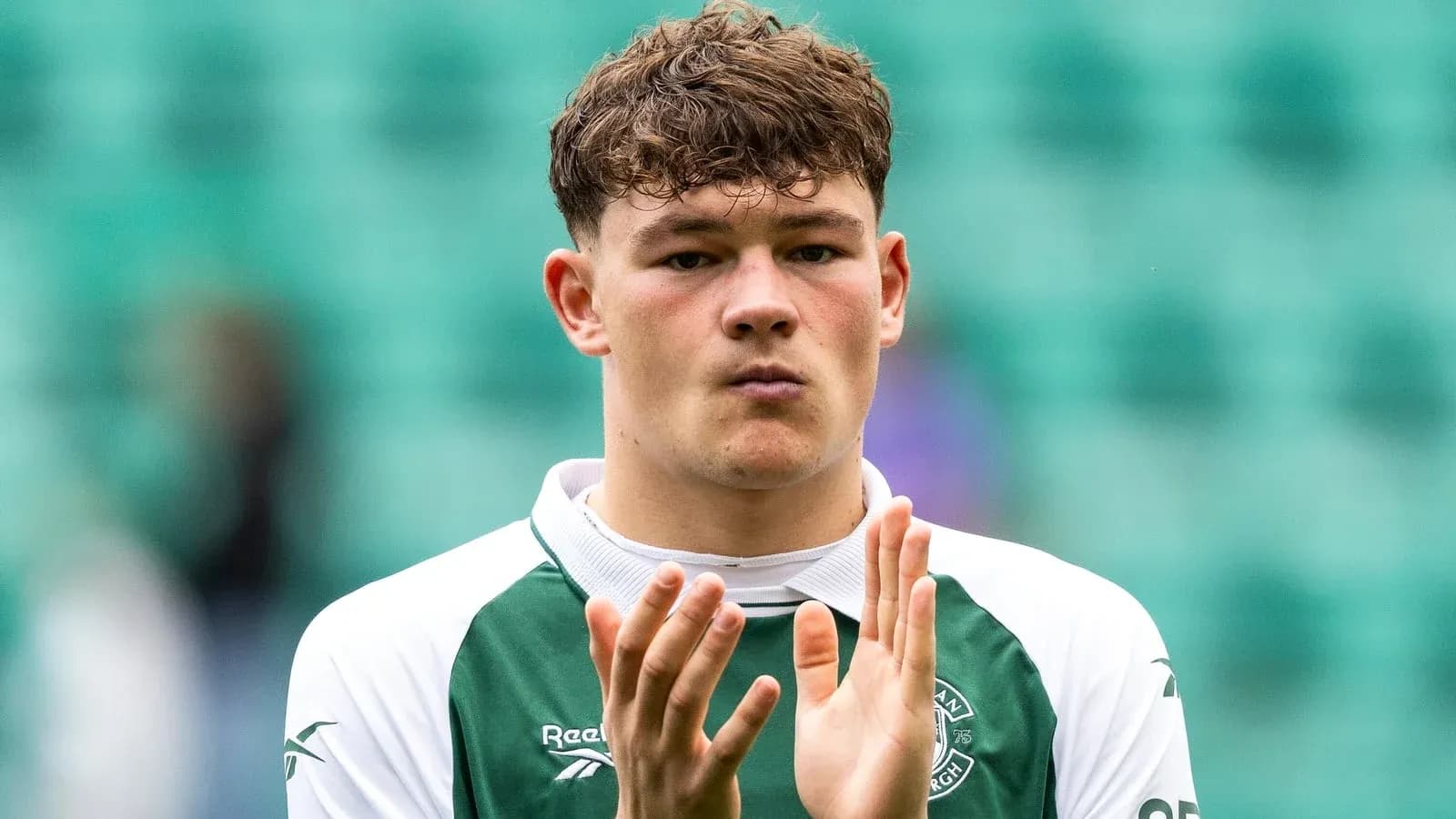 Player applauding in Hibernian FC kit on pitch