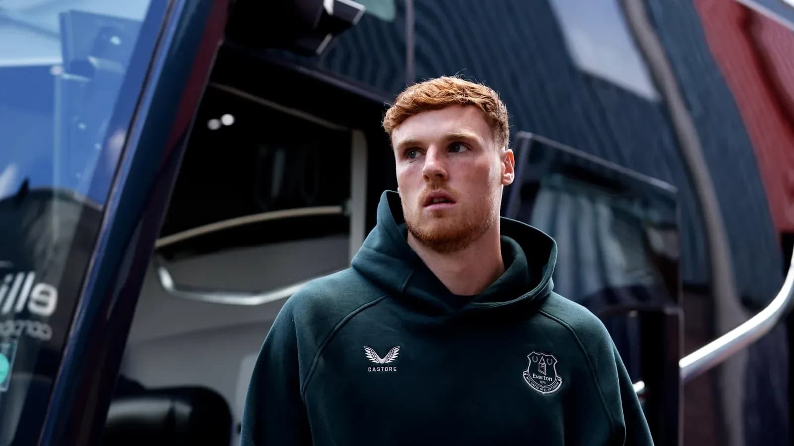 Player wearing Everton hoodie near team bus