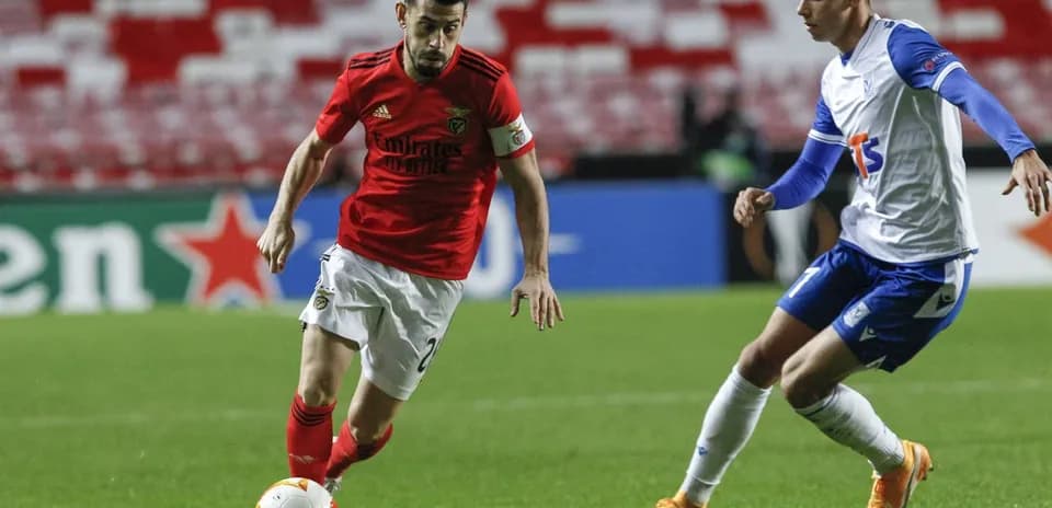 Benfica player dribbling against Lech Poznan opponent