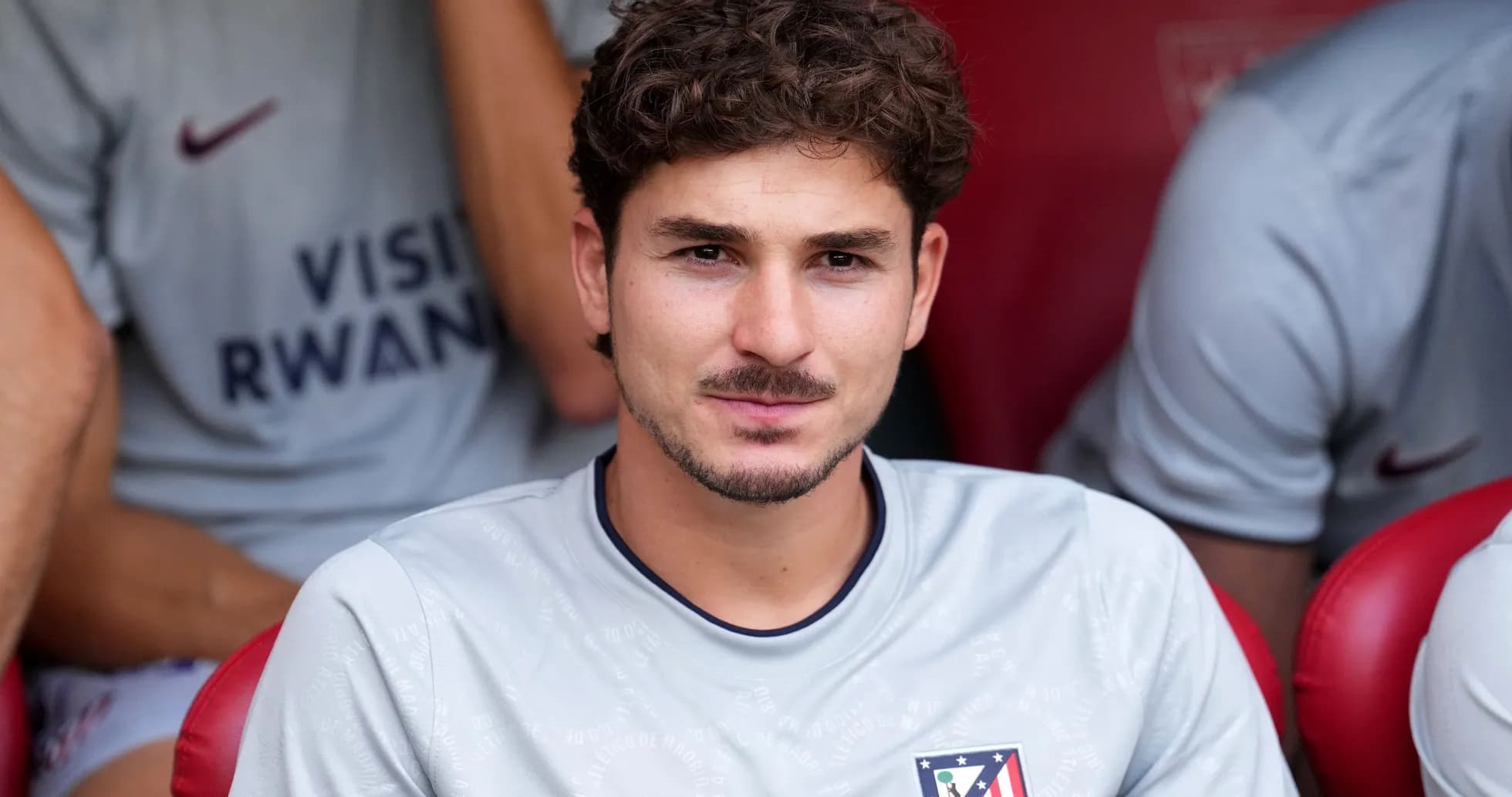 Player seated on bench wearing Atlético Madrid kit
