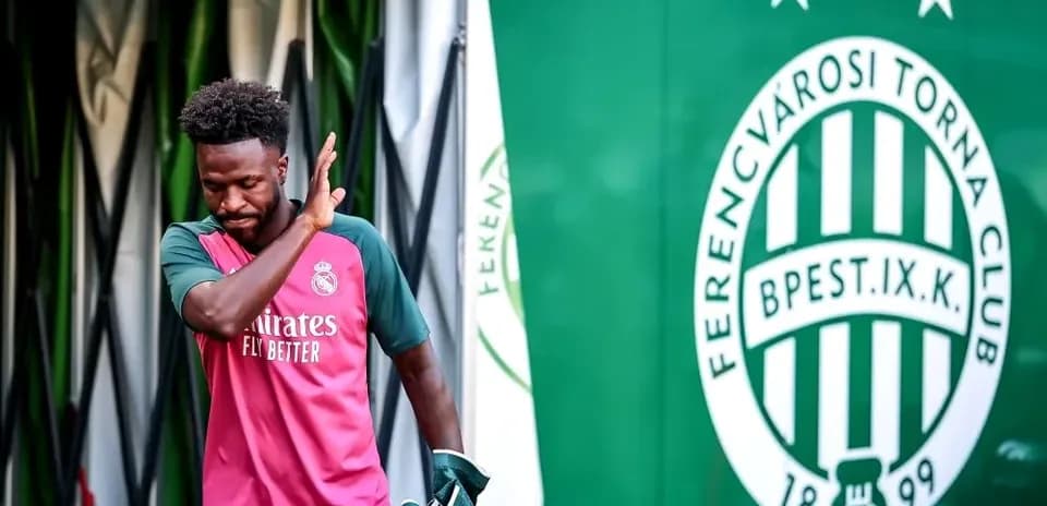 Player in Real Madrid kit walking past club logo