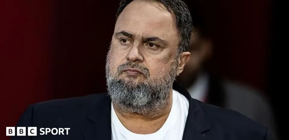 Man with beard in black suit looking serious
