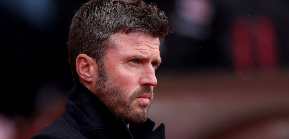 Man in a black coat looking intently on sidelines