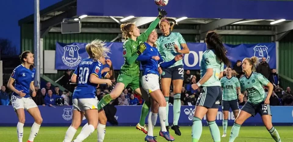 Goalkeeper jumping to catch the ball during match