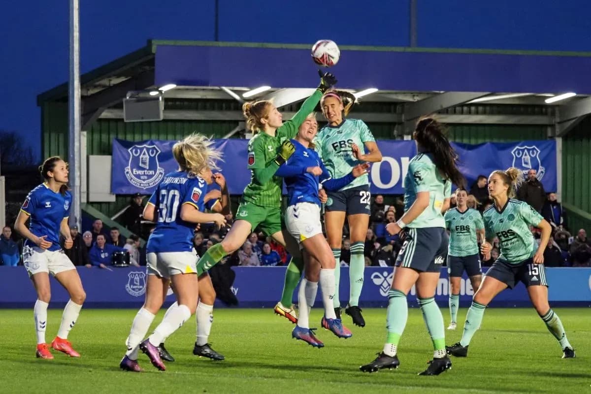 Goalkeeper jumping to catch the ball during match