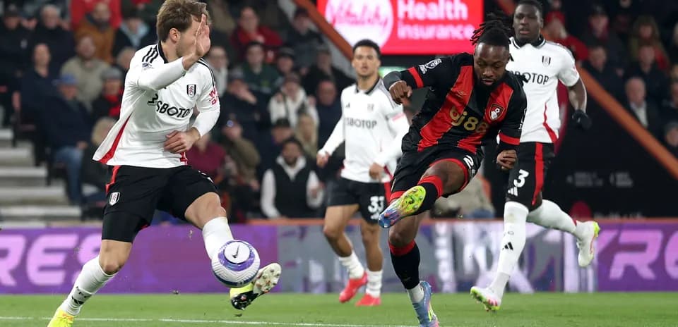 Fulham player challenges Bournemouth opponent for the ball