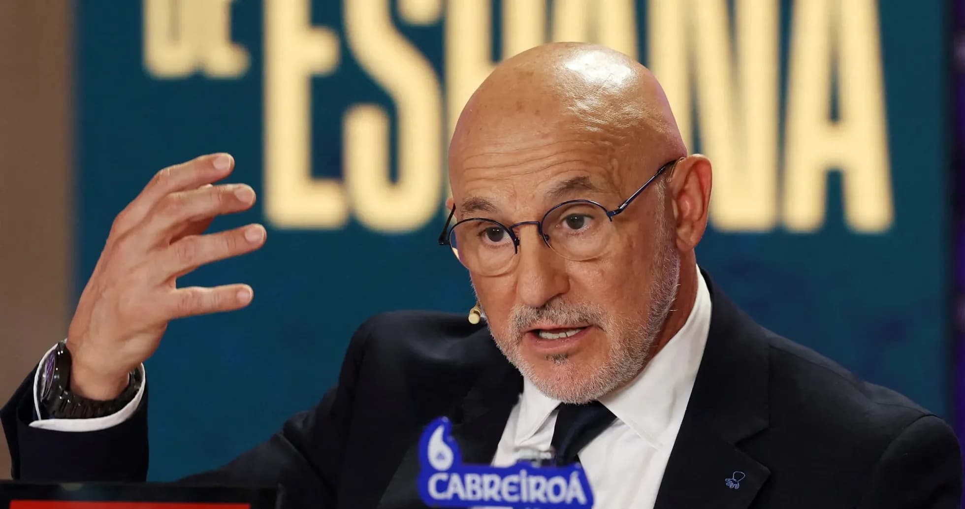 Speaker gesturing during press conference with logos