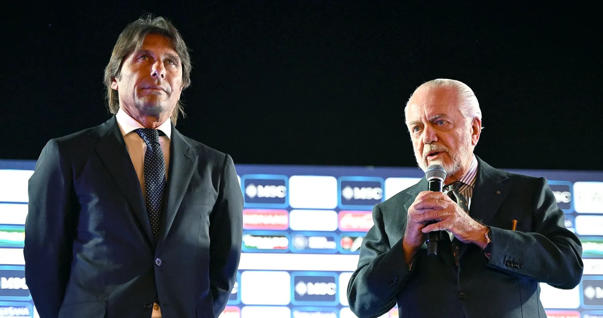 Two men at a press conference with microphones