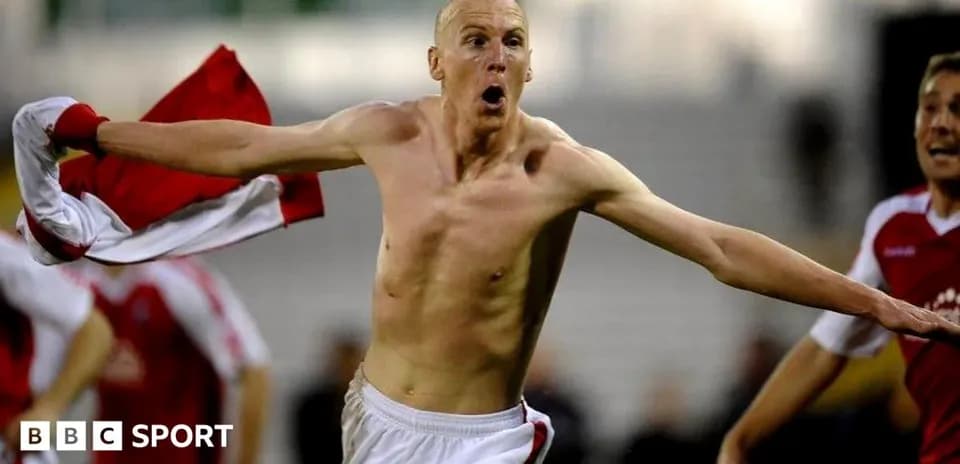 Player celebrating with shirt raised after scoring goal
