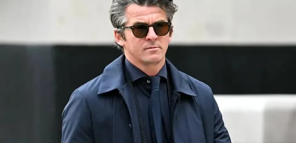 Man wearing sunglasses and a navy coat outdoors