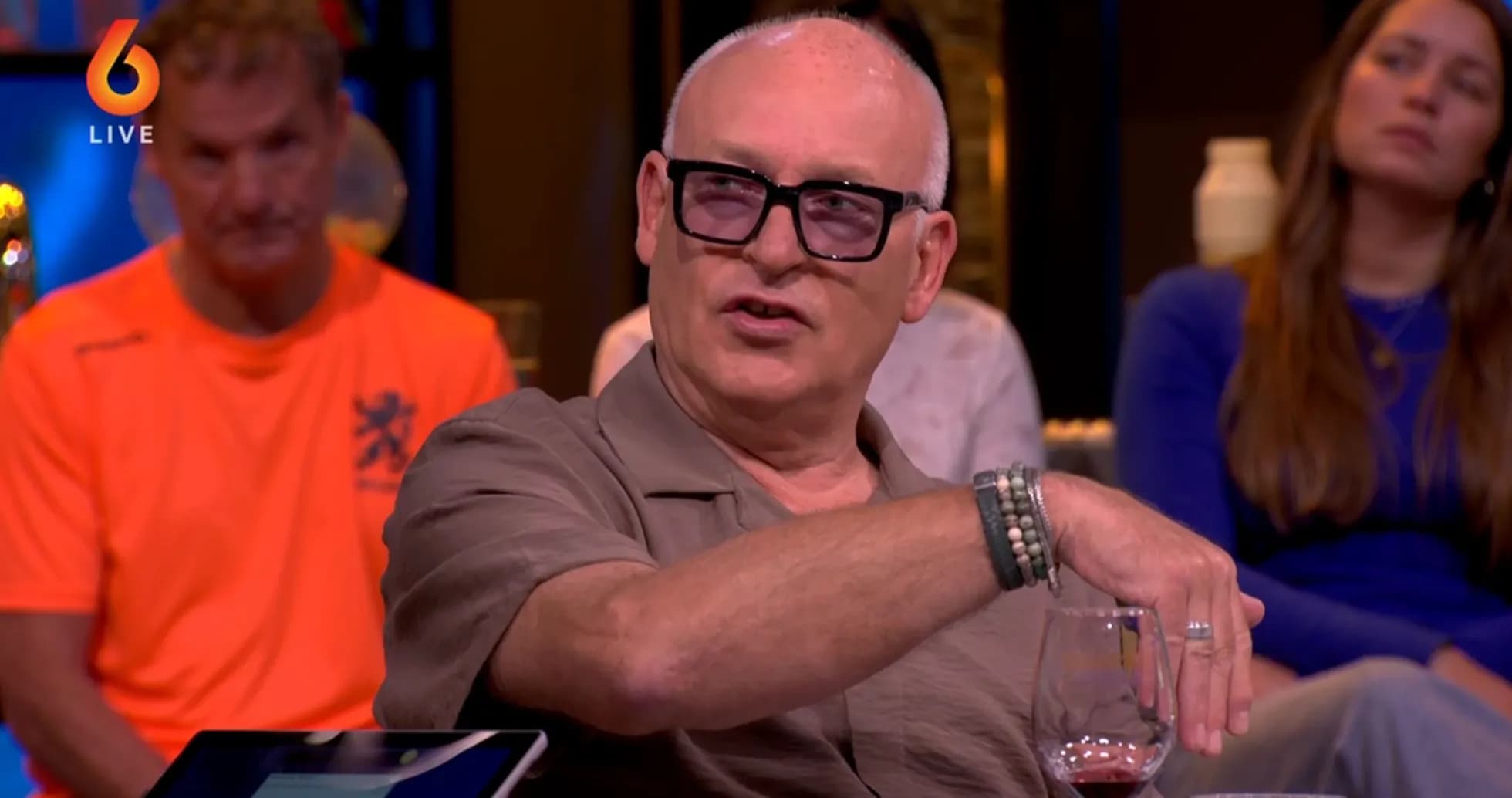 Man speaking with a drink during a discussion