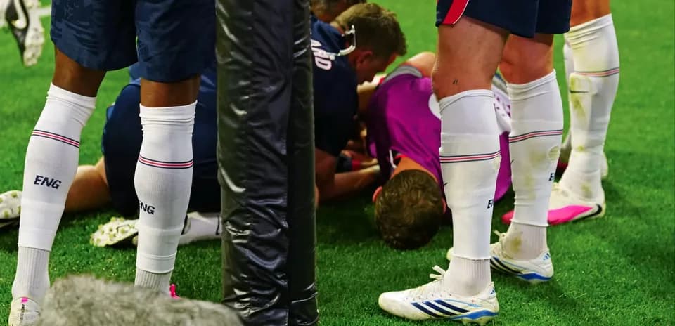 Players surrounding an injured teammate on the field