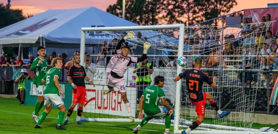 Goalkeeper attempting to save shot during match