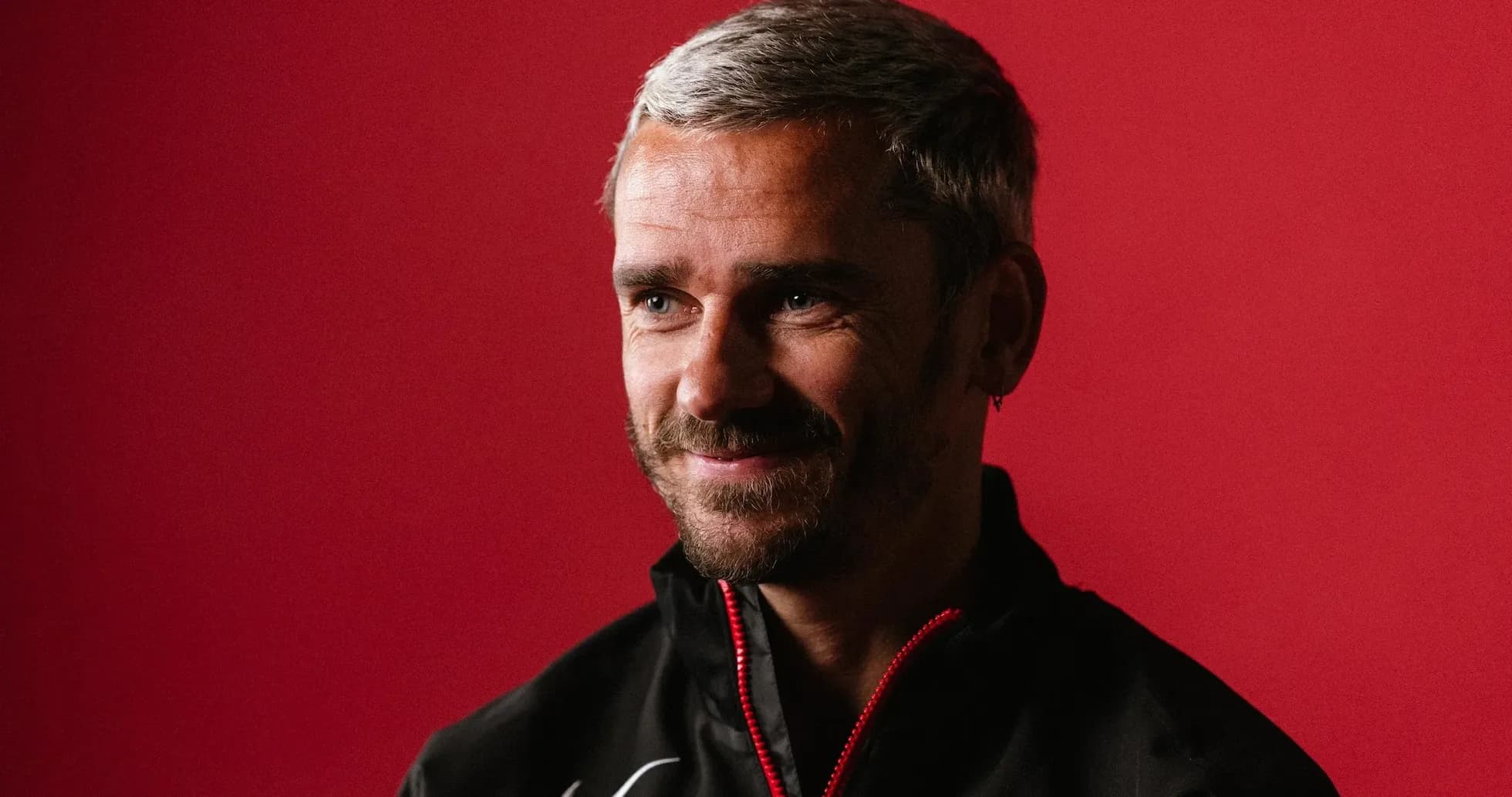 Man with gray hair smiling against red background