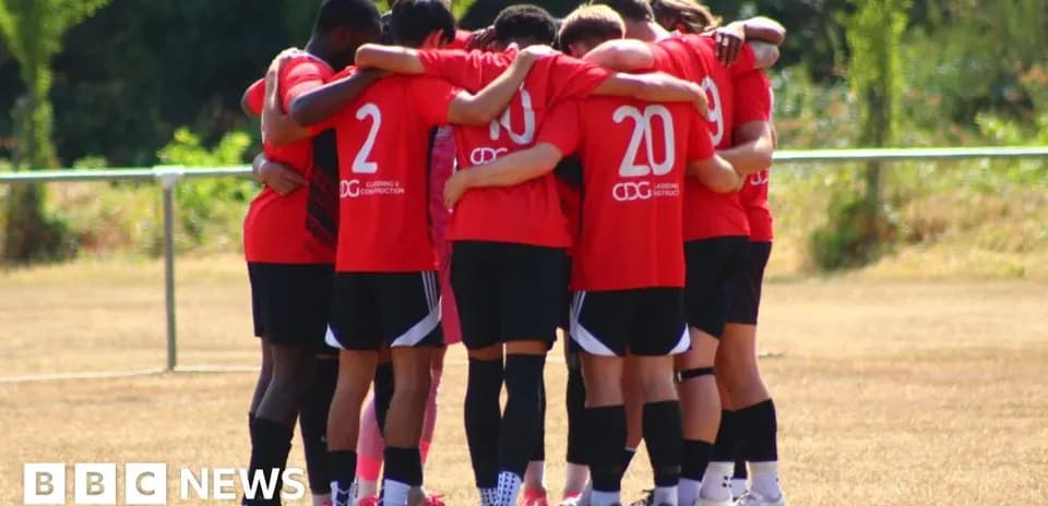 Team in red jerseys huddling on training field