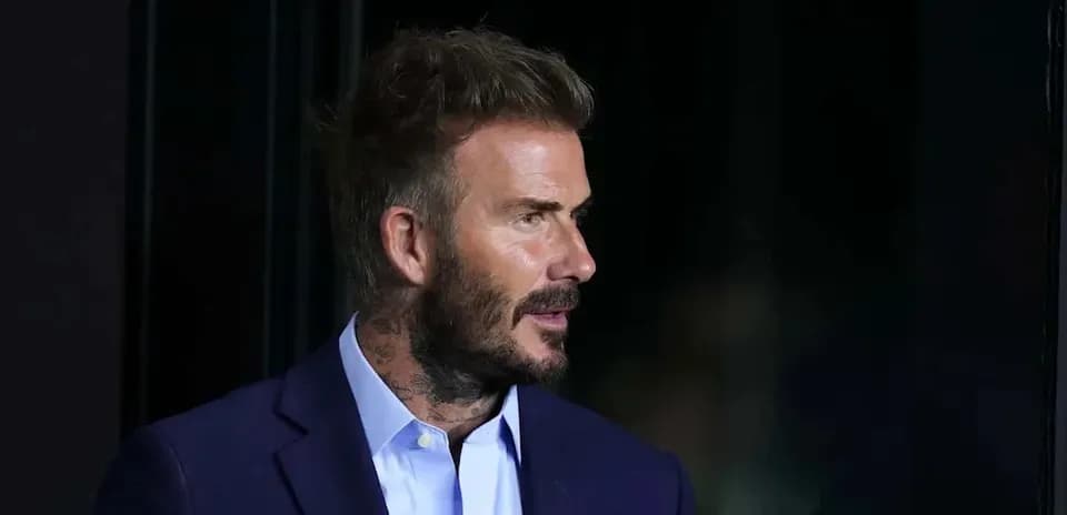 Man in suit with tattoos standing in profile