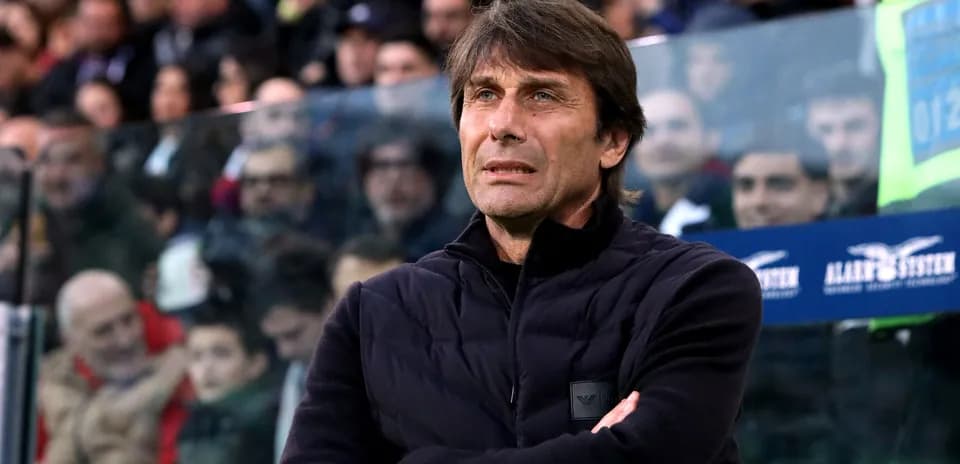 Coach observing match with arms crossed in stadium