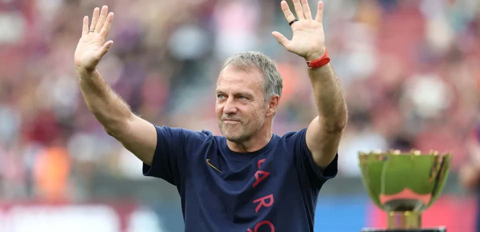 Coach waving to fans next to trophy