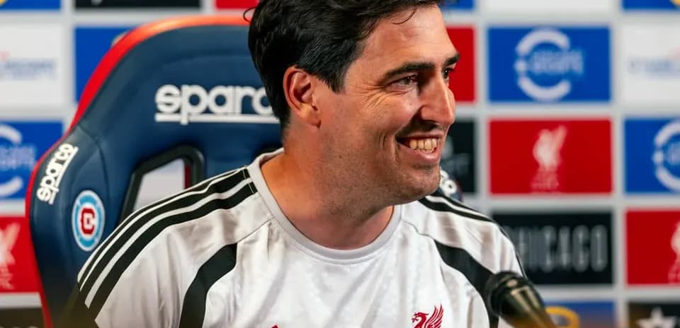 Manager speaking at press conference with Liverpool backdrop