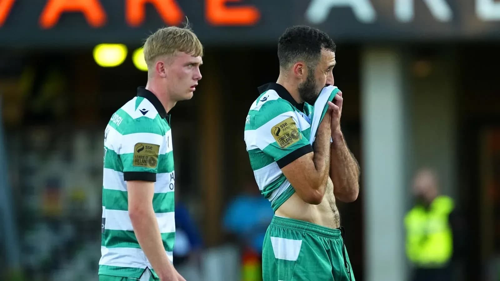 Two players in green and white jerseys after match
