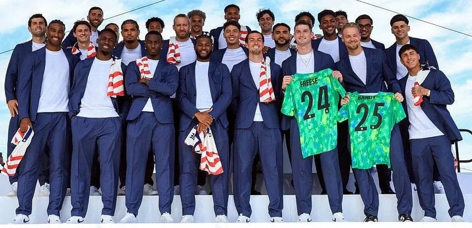 Soccer team posing in suits holding jerseys