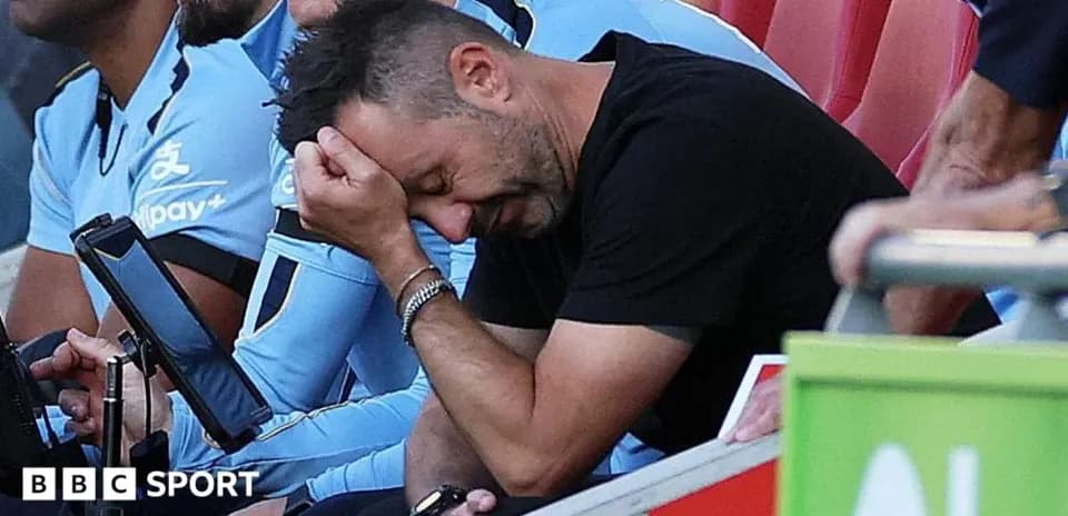 Coach sitting on bench with head in hands