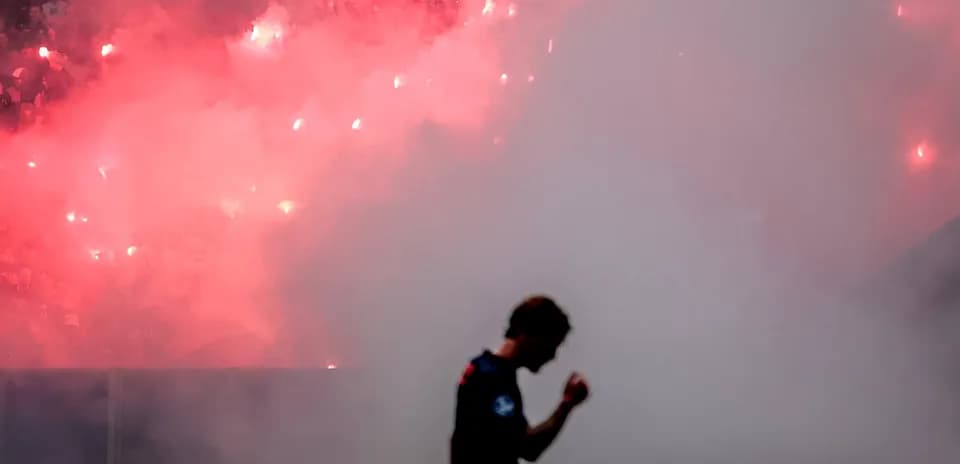 Player silhouetted against smoke and flares