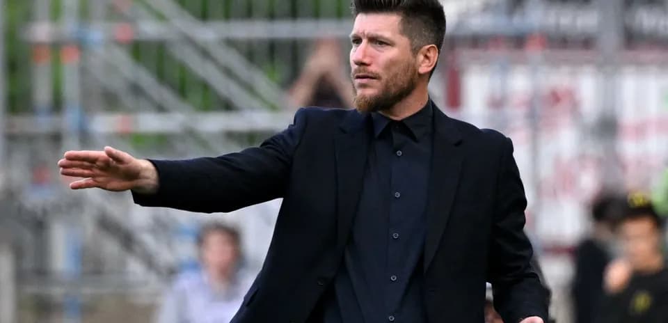 Coach gesturing during a football match on the sidelines