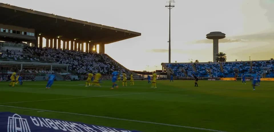 Players competing on the pitch at sunset