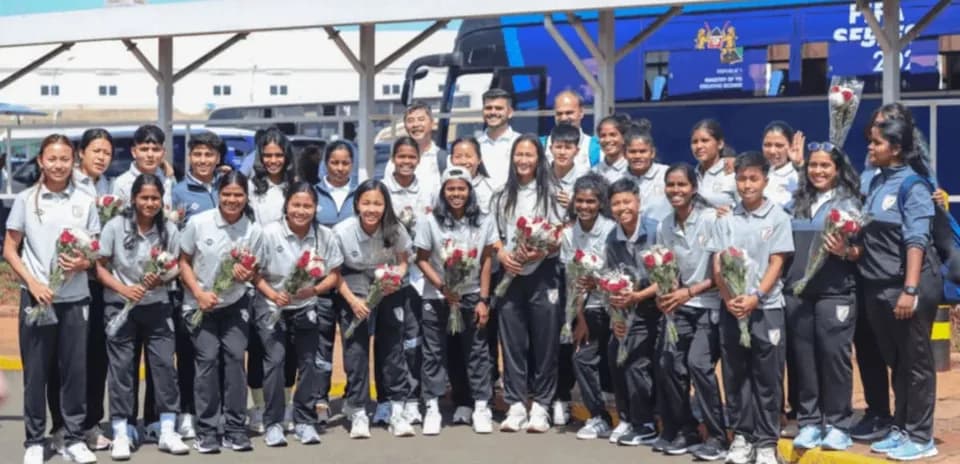 Women's cricket team posing with flowers at airport