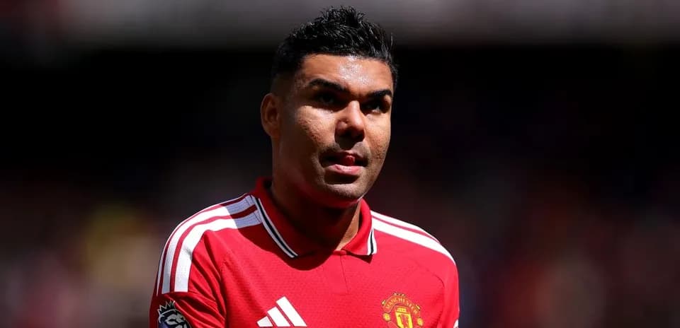 Player in Manchester United jersey walking on pitch