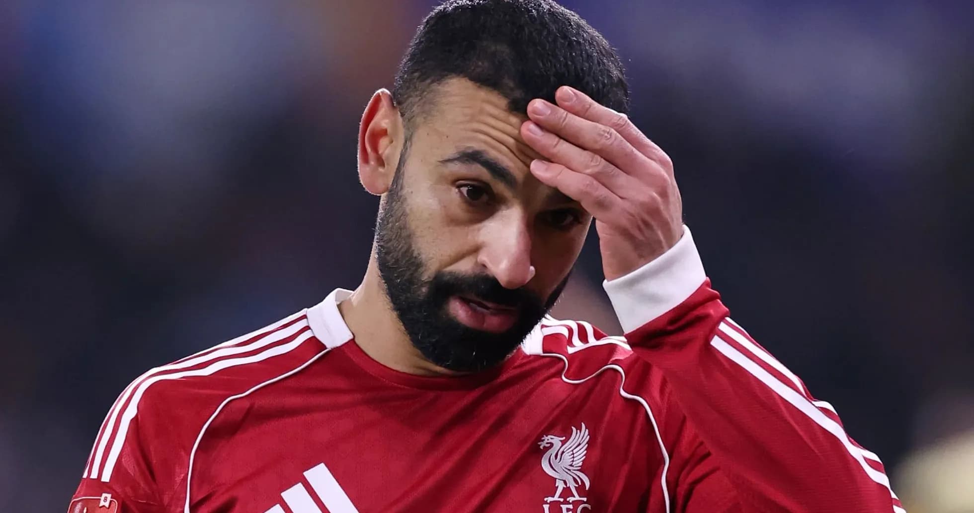 Player in red jersey holding forehead during match