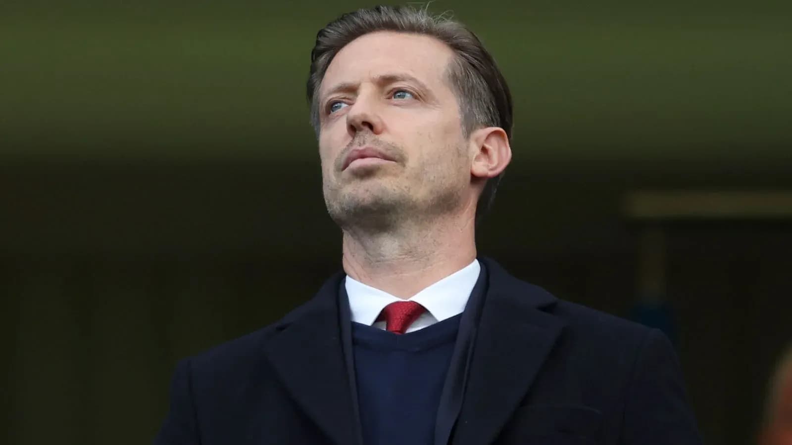 Man in formal attire observing from the stands