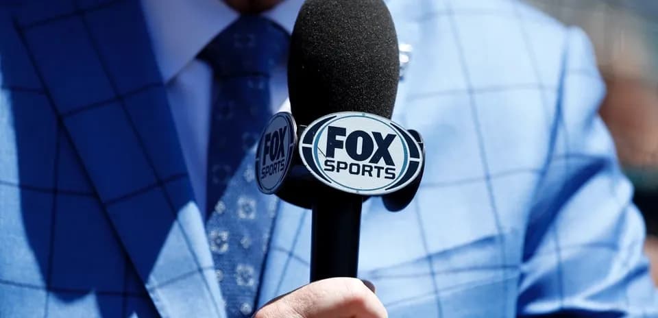 Reporter holding a FOX Sports microphone in suit