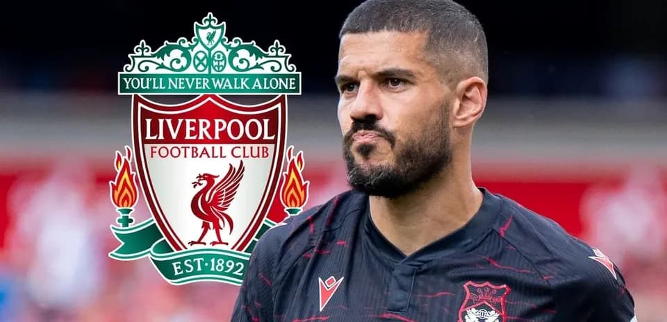 Player in black jersey with Liverpool logo background