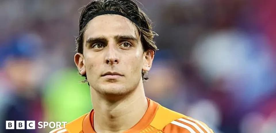 Goalkeeper in orange kit looking towards the camera