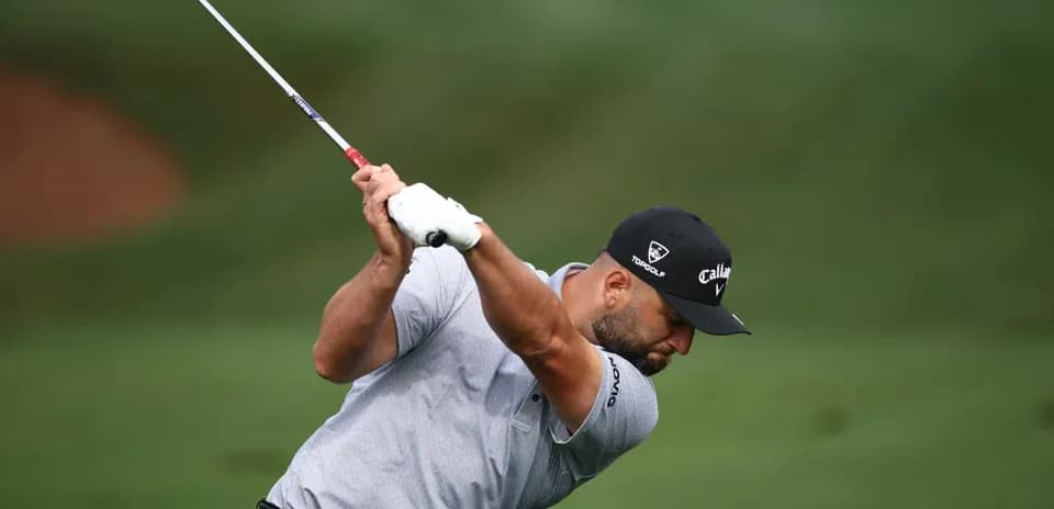 Golfer swinging club on course during play