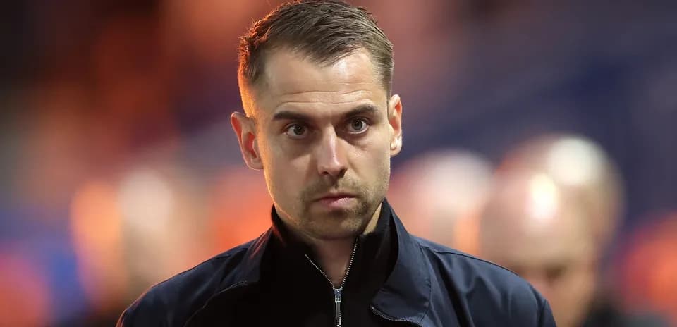 Man in dark jacket walking on stadium path