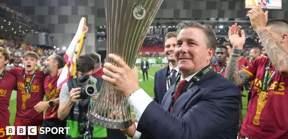 Coach celebrating with Europa League trophy and team
