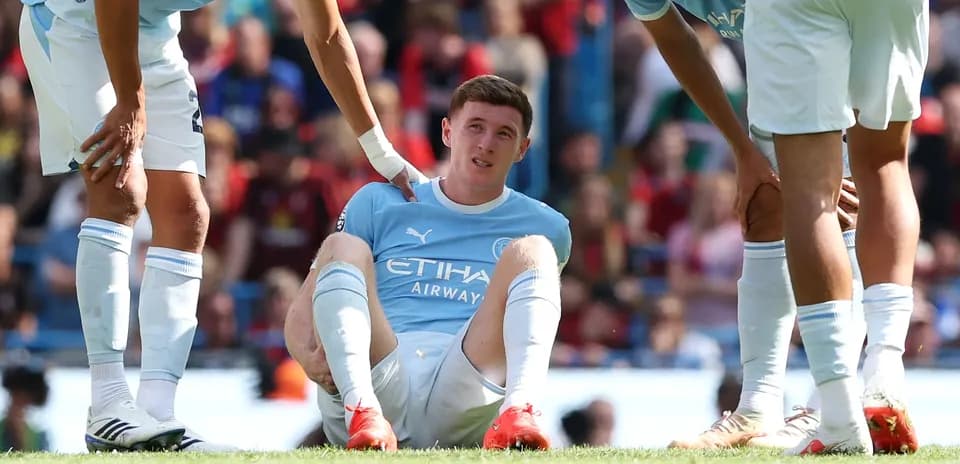 Player sitting on field receiving assistance from teammates