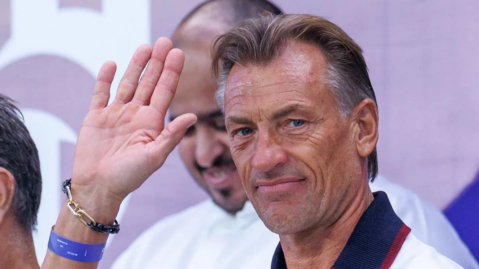 Coach waving during a press event